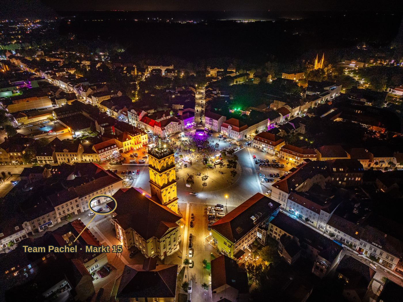 Neustrelitz bei Nacht aus der Luft – der barocke Sternplan führt alle Straßen zum Markt; goldener Ring markiert Team Pachel am Markt 15